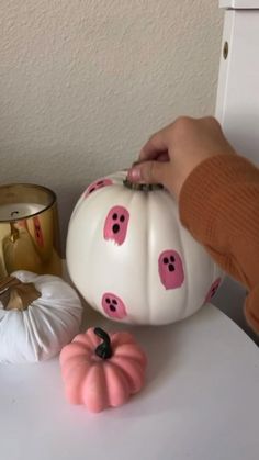 a person is decorating a white pumpkin with pink pigs on it and other decorations