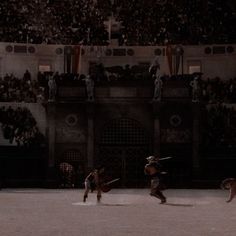 two men are playing baseball in front of an audience at a sporting event with their dogs