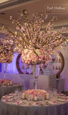 an elegant centerpiece with pink and white flowers is displayed on a round dining table