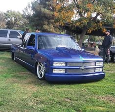 a blue pick up truck parked on top of a lush green field