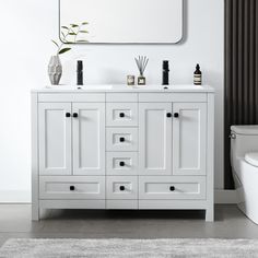 a white bathroom vanity with two sinks and a mirror over the sink, next to a toilet