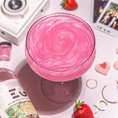 a pink drink sitting on top of a table next to a camera and other items