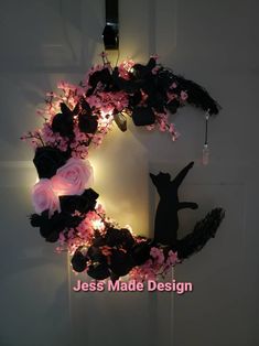 a wreath with flowers and lights hanging on the wall next to a light up cat