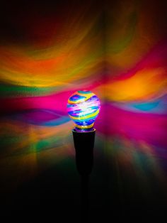 a colorful light is shining brightly on a black background and it appears to be in the shape of a ball