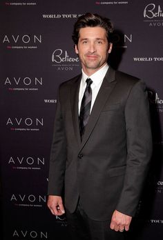 a man wearing a suit and tie standing in front of a red carpeted wall