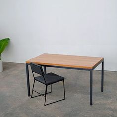 a table and chair sitting next to each other in an empty room with a potted plant on the floor