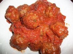 meatballs covered in marinara sauce on a white plate