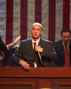 a man standing at a podium with an american flag in the background