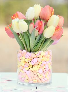 a vase filled with candy corn and tulips