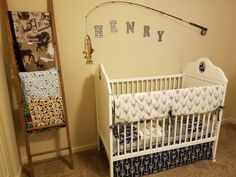 a white crib with blue and white bedding next to a fishing rod on the wall