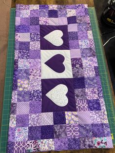 a purple and white quilt with hearts on it