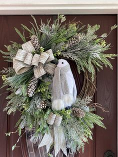 a wreath with an owl and pine cones on the front door