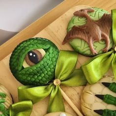 decorated cookies with green ribbons and decorations on a wooden tray, including an animal cookie