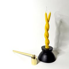 A black candle holder holding a yellow twisted candle to symbolize a twin flame with a brass candle snuffer next to it. Twisted Candle, Twist Candle, Twin Flame, Candle Holder, Twins, Candle Holders, Twist, Candles, Brass