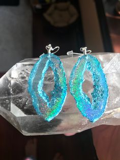 a pair of blue earrings sitting on top of a rock