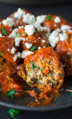 meatballs covered in marinara sauce and feta cheese on a plate with toothpicks