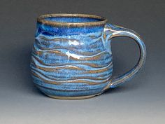 a blue and white coffee mug with waves on the inside is sitting on a gray surface