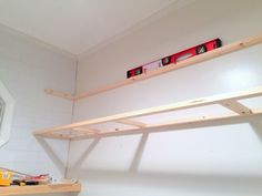 a shelf with some tools on top of it in a room that has white walls