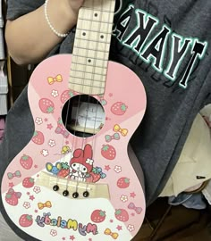 a person holding a pink guitar with hello kitty on it