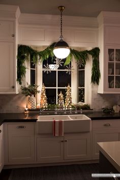 a kitchen decorated for christmas with evergreen garland and pine cones on the window sill