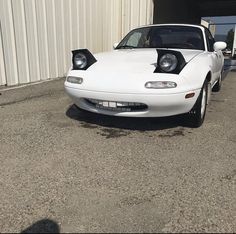 a white sports car parked in front of a building