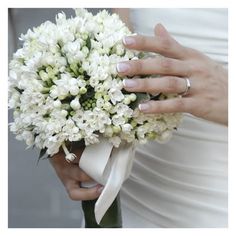 a woman holding a bouquet of white flowers in her right hand and wearing a wedding ring