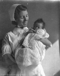 an old black and white photo of a woman holding a baby