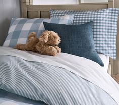 a teddy bear laying on top of a blue and white comforter in a bed