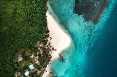 an aerial view of the beach and ocean from above, with houses on land in the foreground