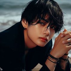 a young man with black hair and piercings on his arm leaning against the beach