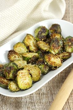 cooked brussel sprouts in a white dish with a wooden spatula