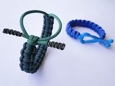 two bracelets with blue and green cords attached to each other on a white surface