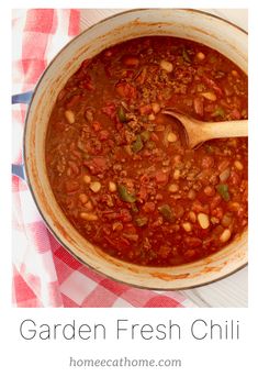 a pot filled with chili and beans on top of a checkered table cloth