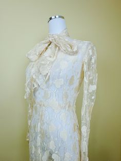 The magic of this dress cannot be overstated. Beautiful cream lace with intricate leaf / floral embroidery design. Fitted int he bodice with gently flared skirt. Pointed princess cuffs. Side snap closures. Comes with a matching tie that can be worn a variety of ways. Does have some stretch but due to age I suggest not stretching too much! Condition: Great! There are a couple of rust colored dots literally not visible when worn and looks practically unworn. Delicate and stunning.  Measurements: Pit to pit 36-38" Waist: 28-30" Hips: 46" Length: 57" ---------- I do not accept returns currently. Please read the description in detail and ask any and all questions before you purchase. However, if you have a problem DO message me, as I am flexible on a case by case basis! ALL ITEMS ARE SHIPPED FR Elegant Cream Lace Wedding Dress, Elegant Vintage White Dress With Scalloped Lace, Fitted Cream Gown With Floral Embroidery, Elegant Cream Gown With Scalloped Lace, Elegant Fitted Lace With Floral Embroidery, Formal Cream Lace Gown, Elegant Vintage Dress With Lace Collar For Vintage Events, Vintage Dresses With Fitted Bodice For Ceremony, Vintage Ceremony Dresses With Fitted Bodice