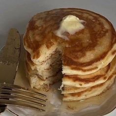 a stack of pancakes sitting on top of a plate next to a knife and fork