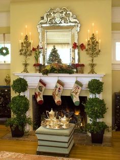 a fireplace with stockings and potted plants on it in front of a mirror above the fire place