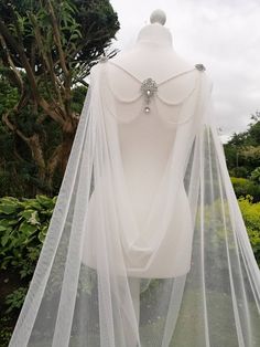 the back of a white wedding dress with beaded neckline and veil on display