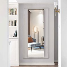 the reflection of a living room in a mirror is seen through an open hallway door