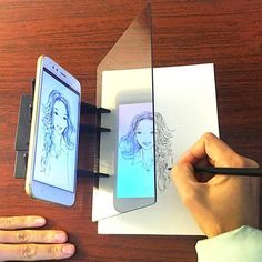 a person is drawing on a piece of paper with a cell phone next to it