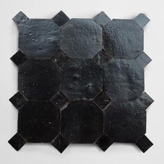 a black tile wall hanging on the side of a white wall