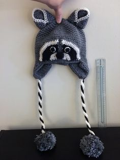 a crocheted raccoon hat hanging on the wall