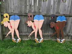 three cardboard cut outs of cartoon characters leaning on each other in front of a fence