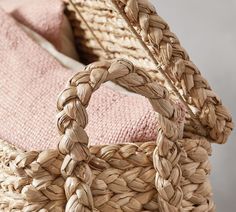 two woven baskets sitting next to each other on top of a pink blanket and pillow