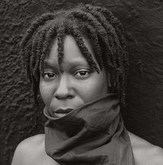 a black and white photo of a woman with dreadlocks wearing a scarf around her neck