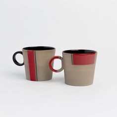 two coffee mugs sitting side by side on a white surface, one with red and the other black