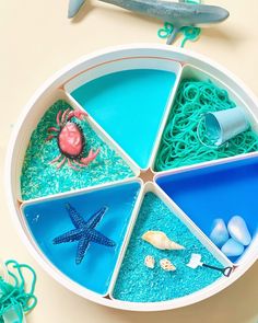 a bowl filled with different types of sand and sea animals on top of a table