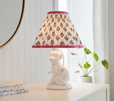 a lamp that is sitting on top of a table next to a mirror and some books