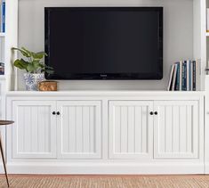 a flat screen tv mounted on top of a white entertainment center with bookshelves