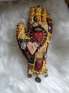 an oven mitt made out of fabric and beads on top of a white fur covered floor