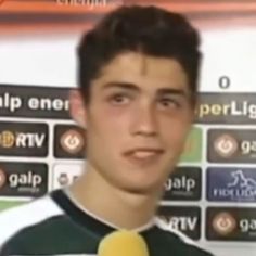 a young man wearing a tie and holding a microphone in front of a soccer field